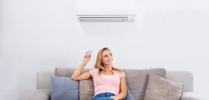 foto de mulher sentada no sofá ligando ar condicionado